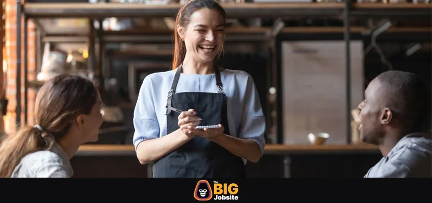 Attractive waitress laughing at African American man joke, serving customers