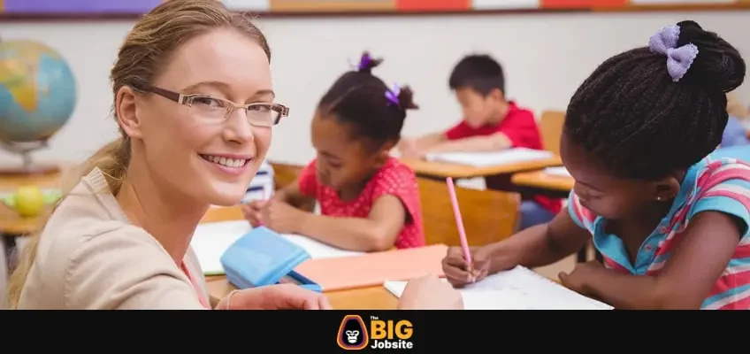 A woman kneeling next to a student's desk