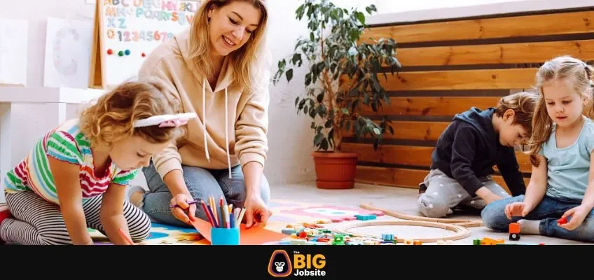 Portrait of young smiling woman teacher sitting near colorful pencils, different toys with children