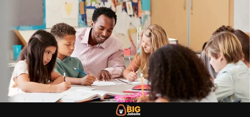 Male teacher works with elementary school kids at their desk