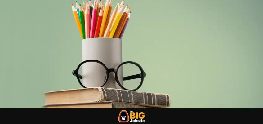 Coloured pencil pot with glasses on a stack of old books